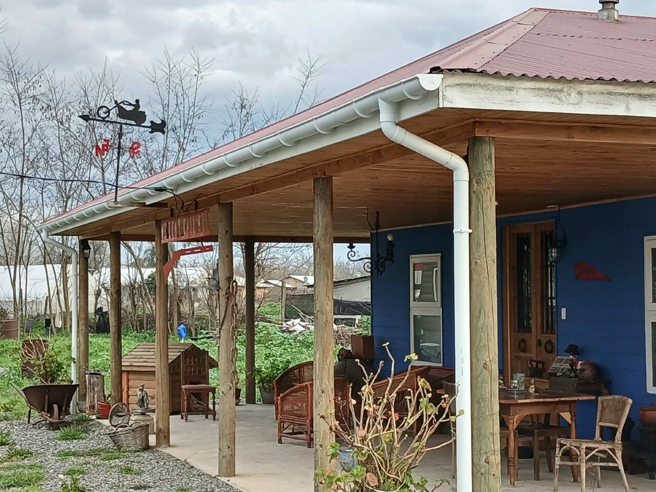 Terraza cubierta de Antigüedades El Pirata con muebles de mimbre y madera, ambiente rústico-colonial