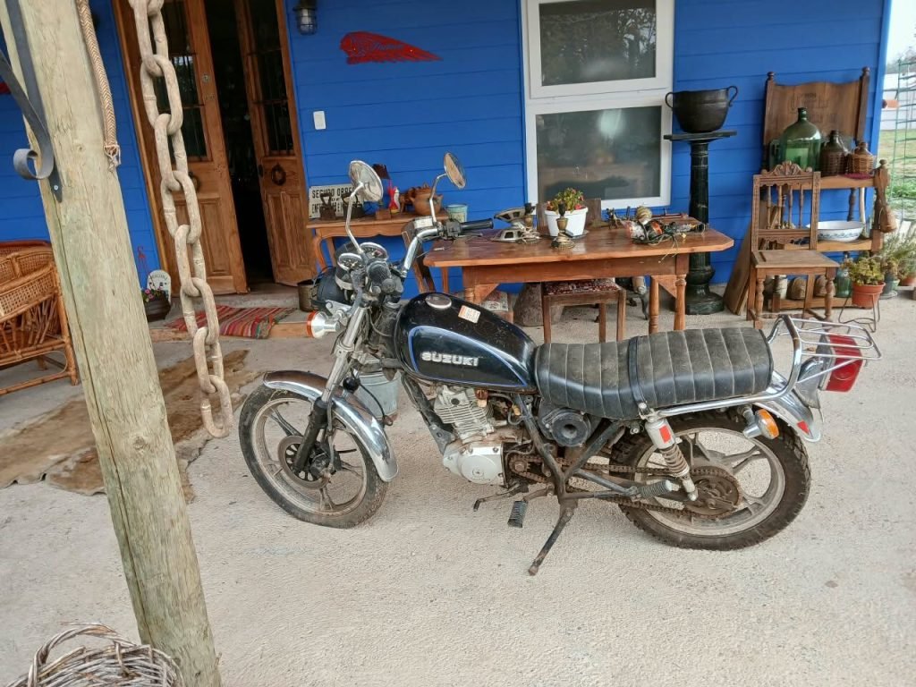 Motocicleta Suzuki junto a mesa de antigüedades
